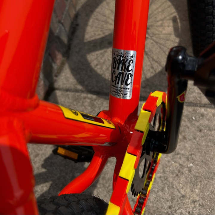 Bike Chain Cover on a vibrant BMX bike with yellow and orange two-tone colors and a unique Bike Cave sticker.