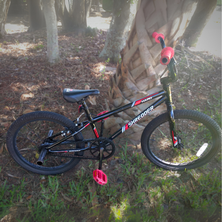 BMX Bikes 16 inch and larger - black bike with red accents in grass near trees