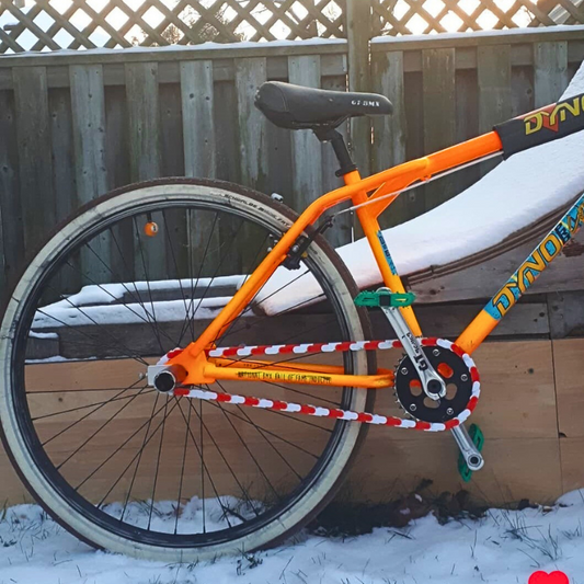 SE Bike Chain showcased on a bright orange bicycle in winter, highlighting two-tone design with snow background.