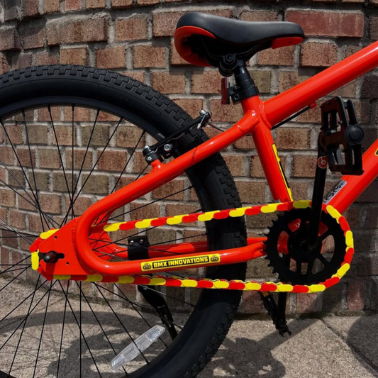 Bike Chain Cover installed on a vibrant orange bike, featuring bright yellow and orange two-tone design.