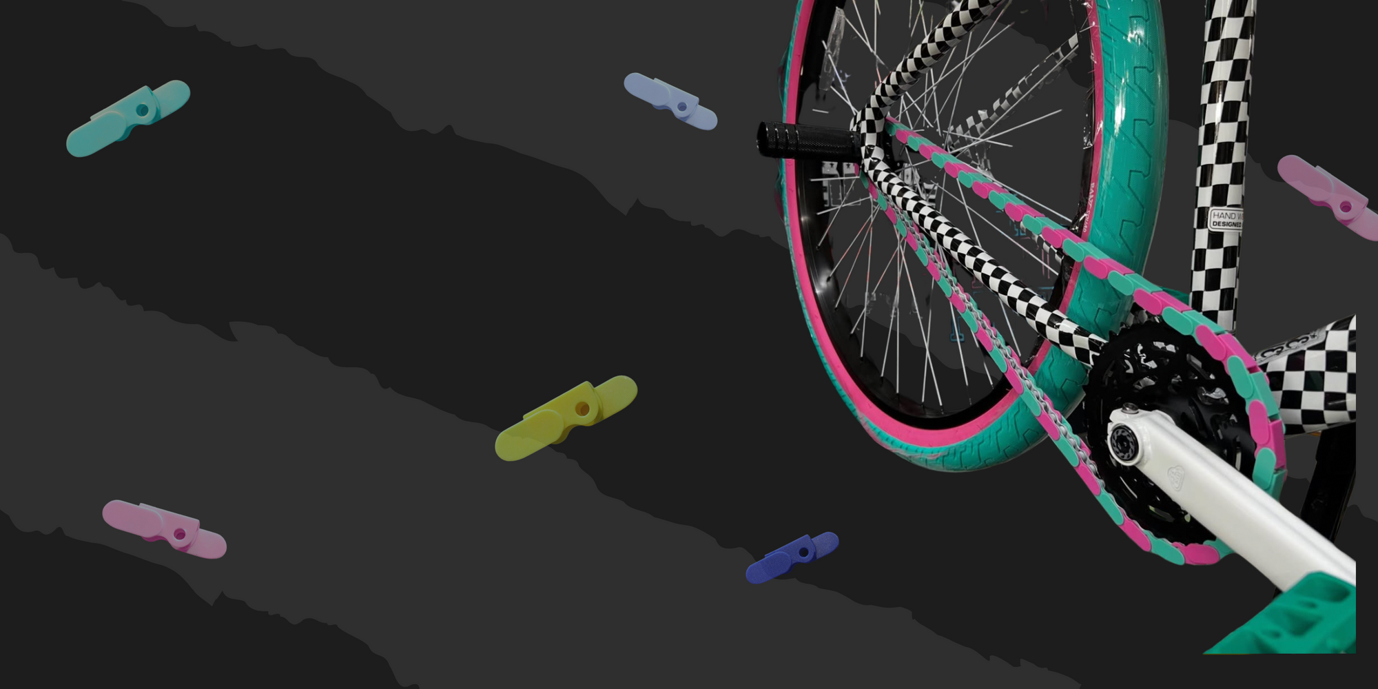 Colorful BMX bike with Pink & Teal Insane Chains Caps on a dark background with checkered pattern
