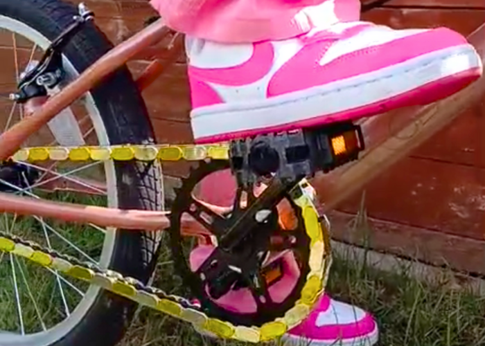 Close-up of a bicycle chain with Insane Chain Gold and Chrome Caps protecting the riders sneakers