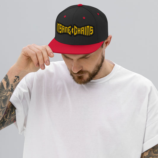 Man wearing Insane Chains Snapback Hat with bold logo in a stylish urban setting.