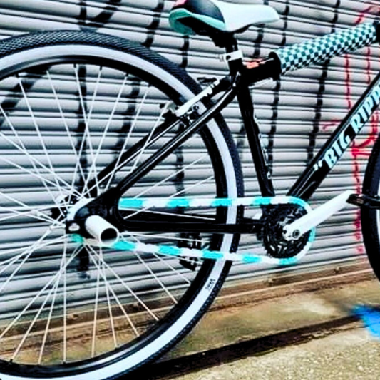 SE Bike Chain on a black bike with white and teal accents against a graffiti background.