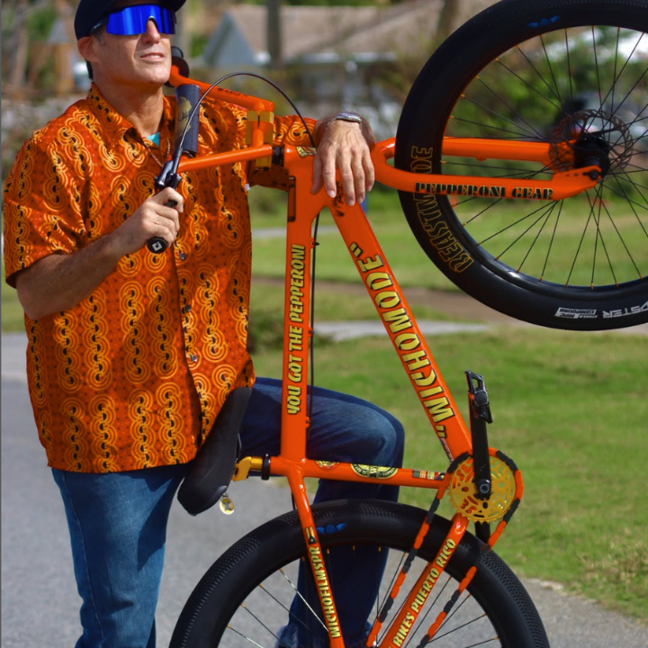 Bike Chain Cover styled on a vibrant orange bike with a rider showing off a bold pose outdoors.