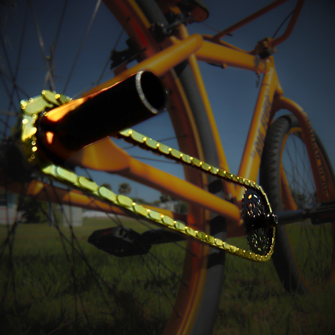 Bike Chain Cover – Gold snap-on caps on a bicycle chain against a vibrant orange bike.