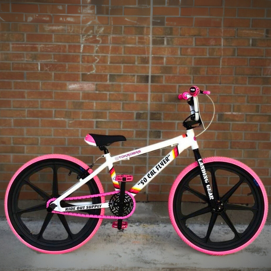 BMX Bikes Pink with snap-on chain caps, showcasing a custom pink setup against a brick background.