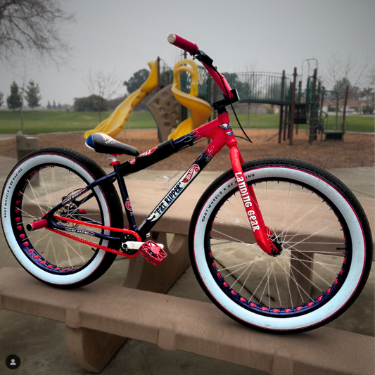 BMX Bikes Red with snap-on chain caps and white tires in a park setting, showcasing bold red and black design.