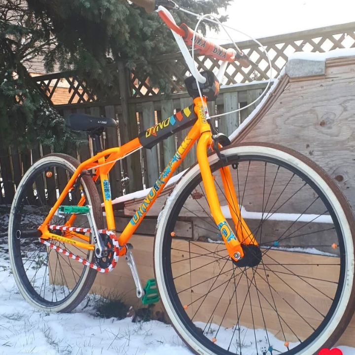 SE Bike Chain with orange and white design showcased on a bike in snow, emphasizing bold style and vibrant colors.