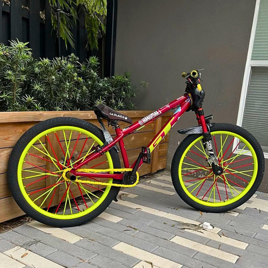 Customizable BMX Bikes with yellow snap-on chain caps, showcasing vibrant red and yellow design in a garden setting.