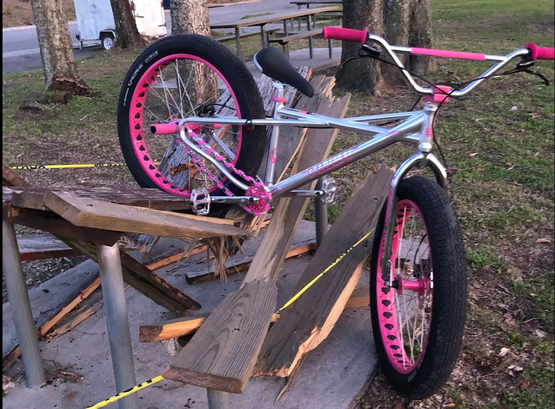 BMX Bicycle with pink rims and pink chrome Insane Chains Caps on a wooden bench outdoors