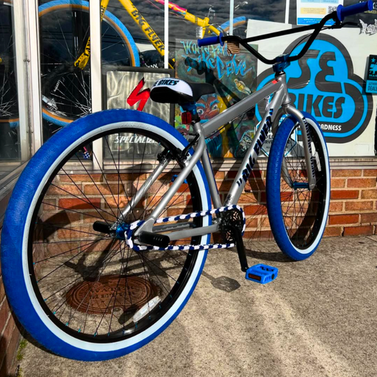 Customizable BMX Bikes with blue tires and chrome frame showcasing unique design in front of bike shop.