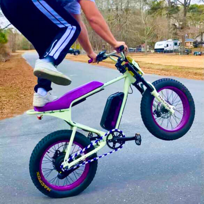 Macfox bike with purple and white two tone design, rider performing a wheely on a road.